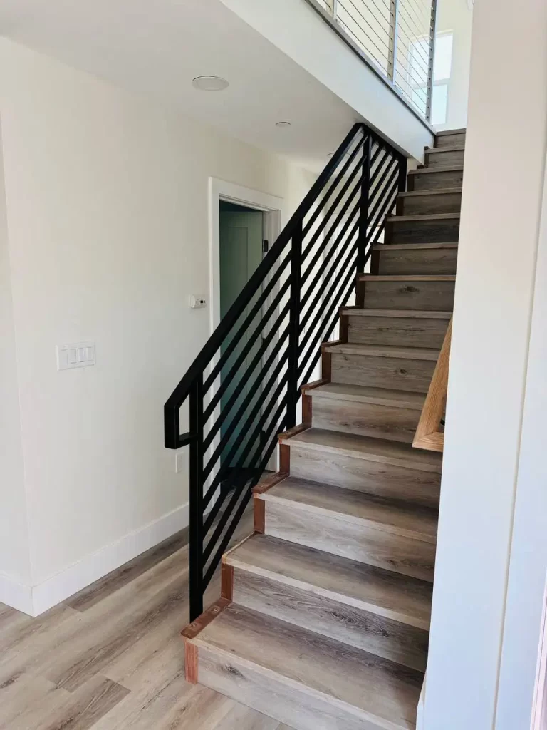 Elevated patio with black horizontal metal railings and a modern exterior design.