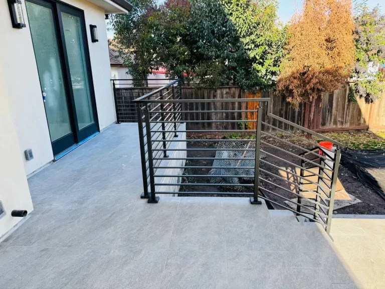 Covered patio with horizontal black metal railings and stair access.