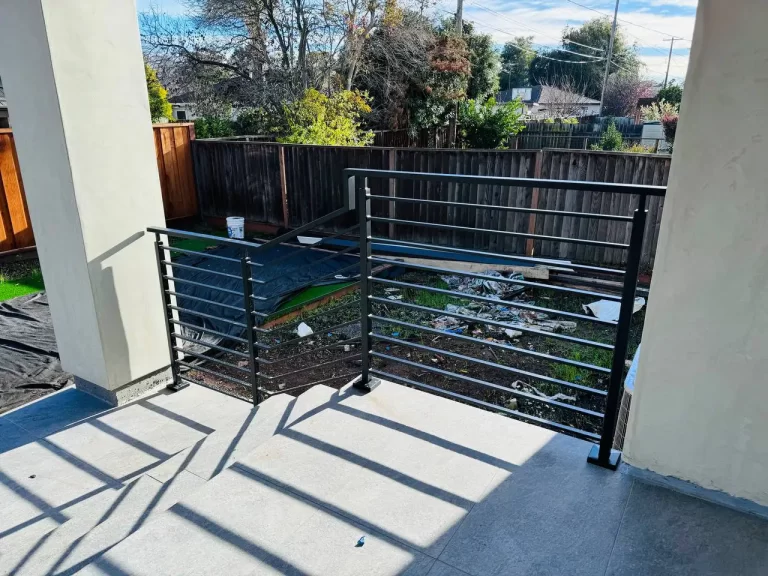 Outdoor staircase with black horizontal metal railings leading up to a deck.