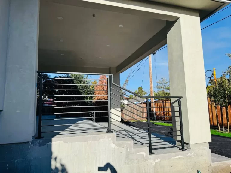 Modern metal railing system with black horizontal lines, complementing a contemporary house exterior.