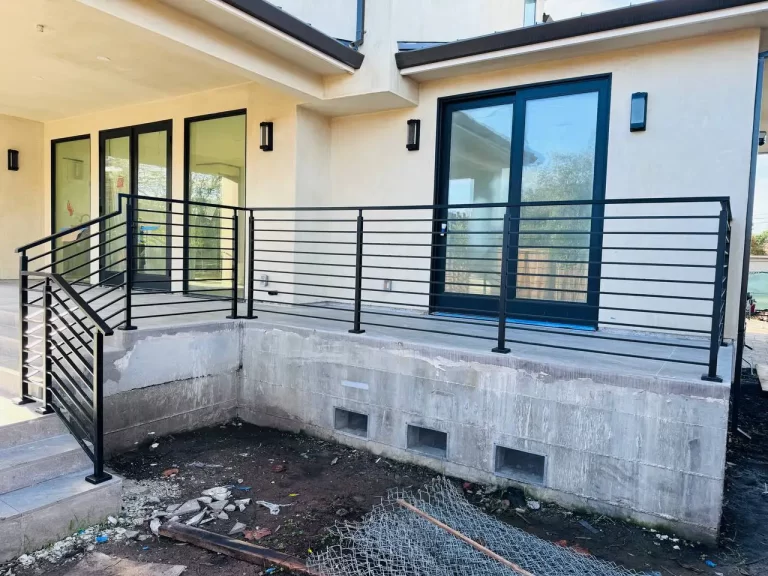 Black metal railing installed on an interior staircase with wood steps and a clean, modern design.