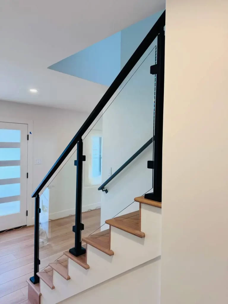 Hallway with glass railing featuring black accents, creating a seamless modern look.