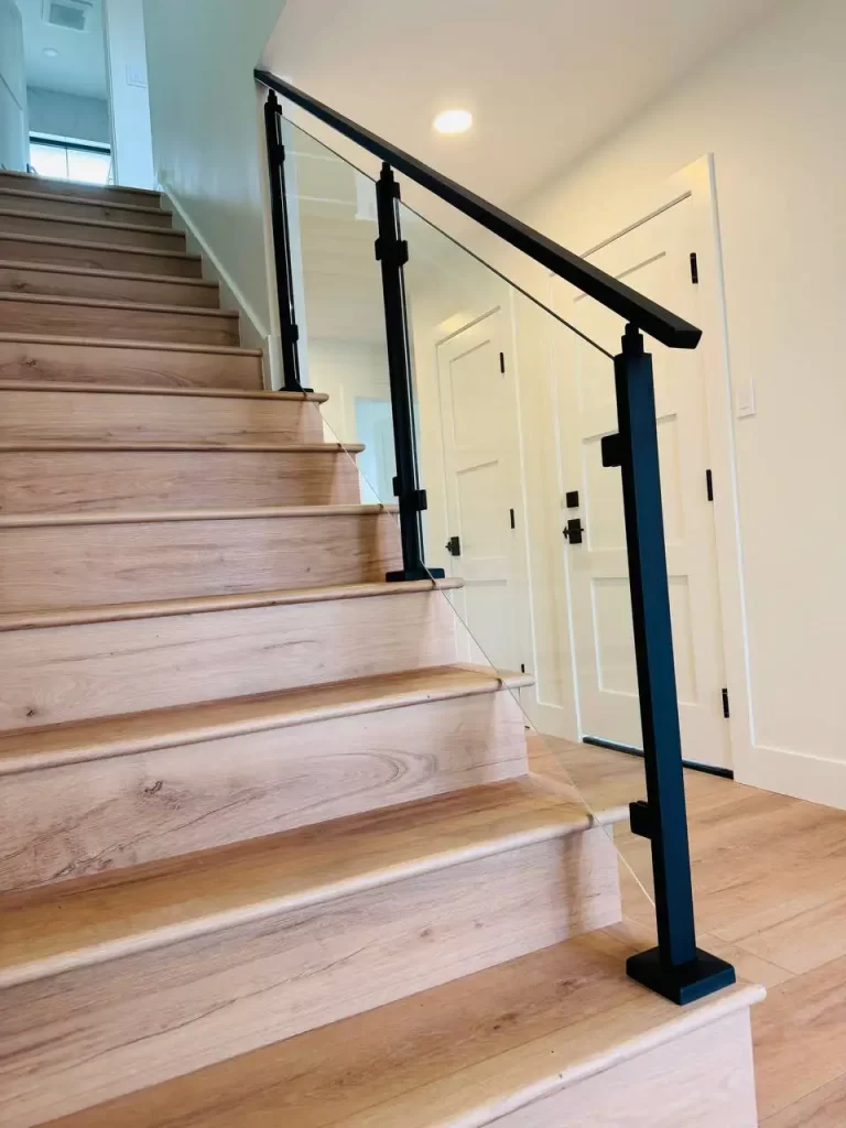 Minimalist staircase design with black metal handrails and clear glass panels.